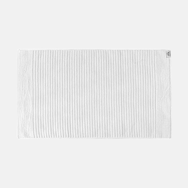 White bath mat with a subtle pattern on a white background
