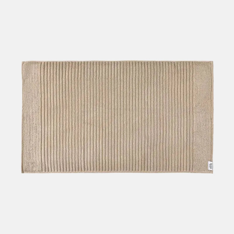 Beige textured bath mat on a white background