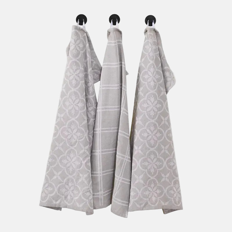 Three patterned towels hanging on a rack against a white background